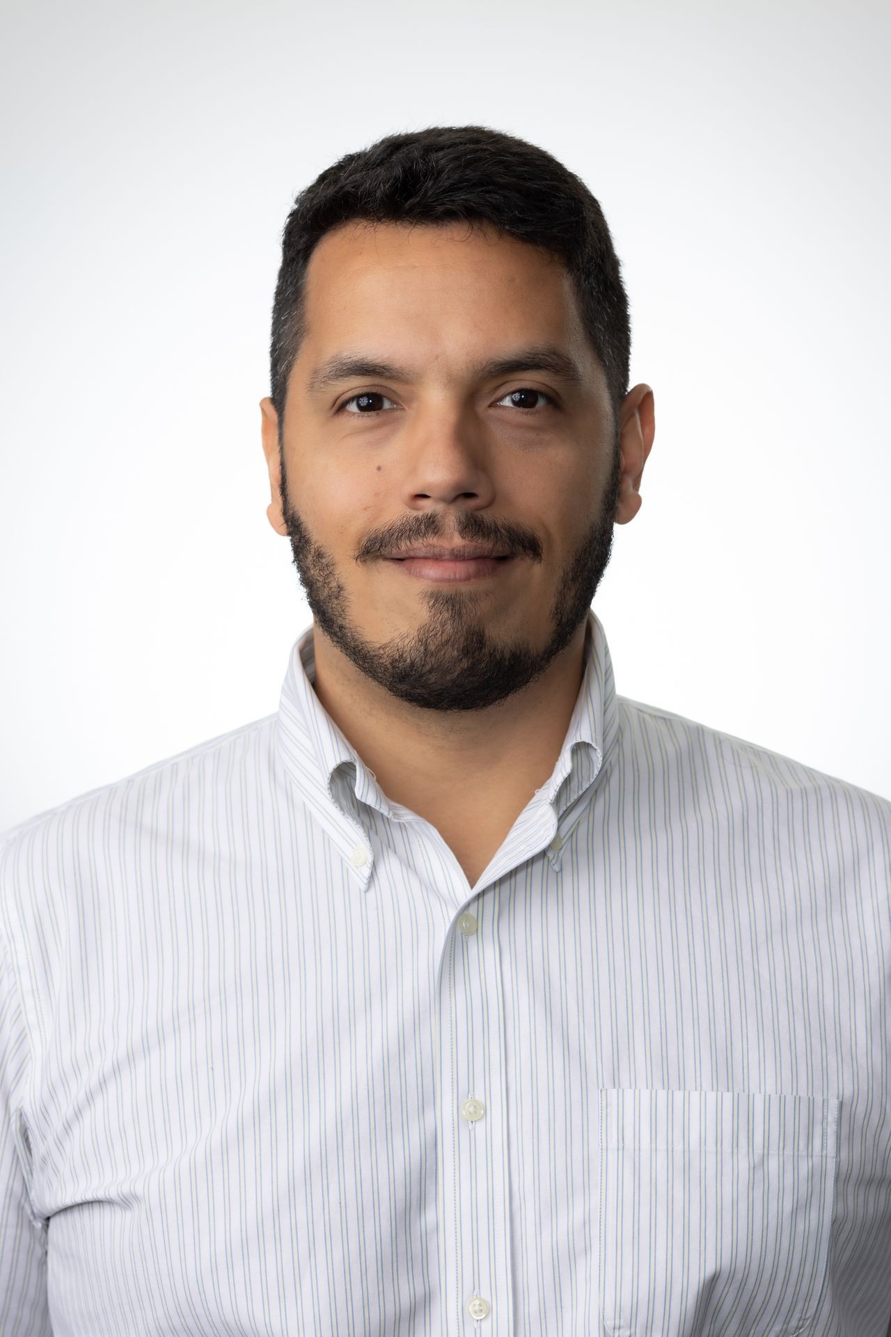 Man with short hair and beard in a white striped shirt against a neutral background.